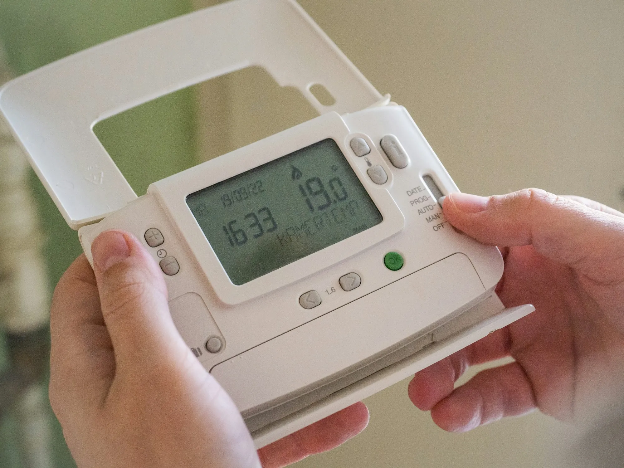 Hands holding a programmable thermostat control