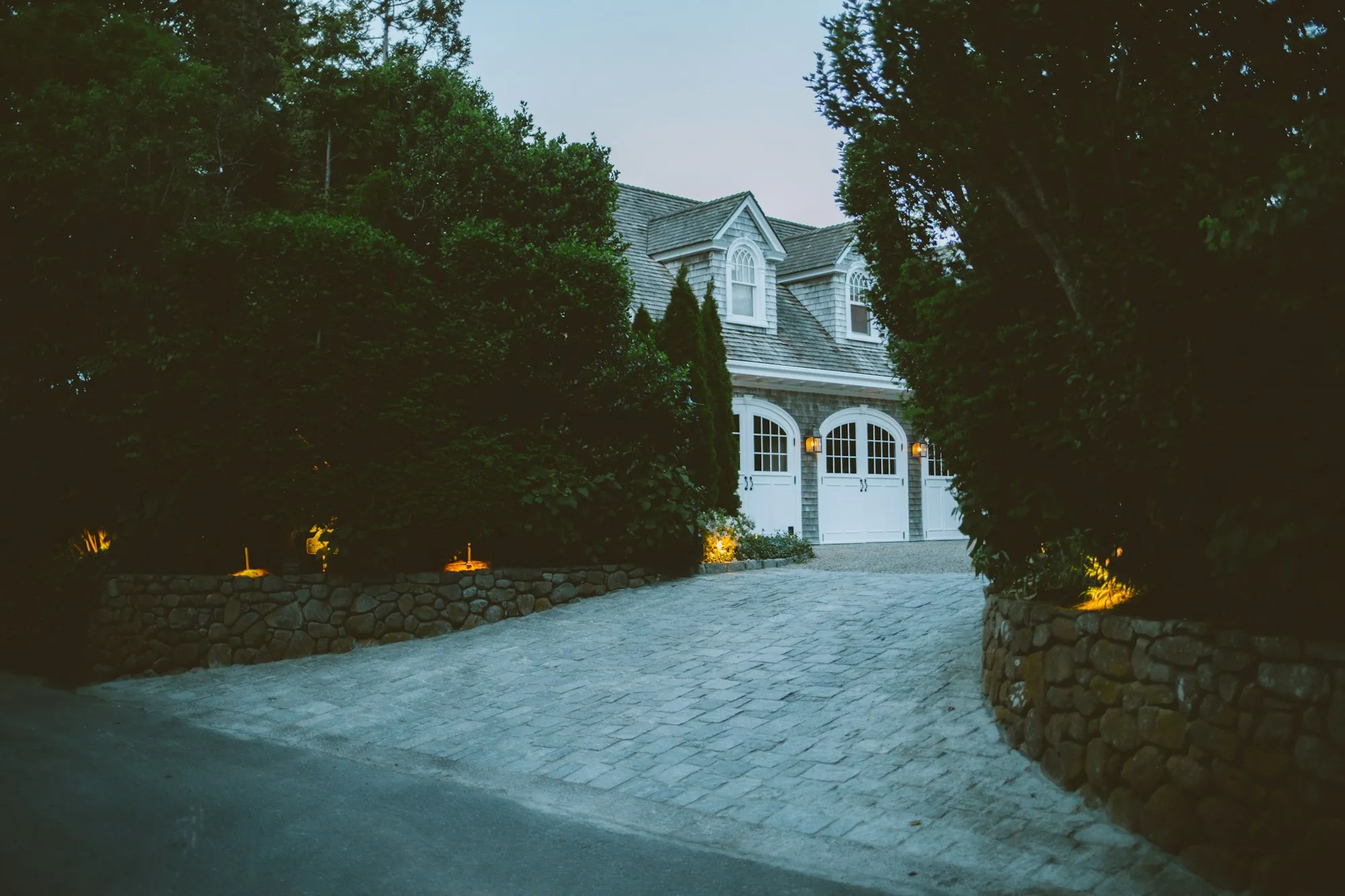 Home with a lit garage and driveway lights at dusk
